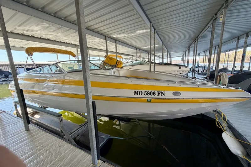 The Image of 2006 Crownline 266 BR boat with yellow accents docked in a covered marina. - 0