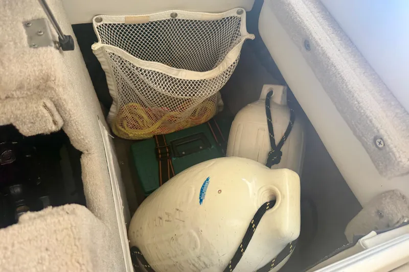 Slide: The Image of Storage compartment in a 2006 Crownline 266 BR boat with jugs and netted items. - 11