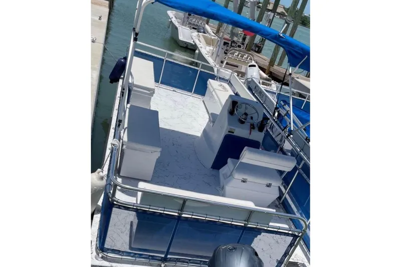 Slide: The Image of 2021 A&M Manufacturing model 20 boat with blue canopy and seating, docked at marina. - 3