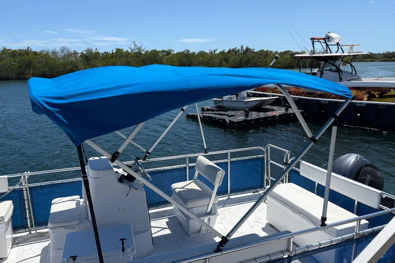 Slide: The Image of Pontoon boat with blue canopy by A&M Manufacturing, model Salty, 2021, docked on a sunny day. - 34