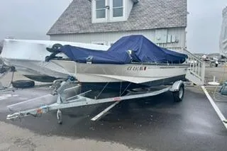 Slide: The Image of 2014 Boston Whaler Montalk boat on trailer, covered with blue tarp, parked near building. - 1