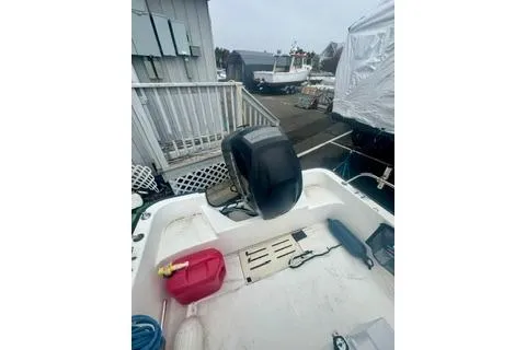 Slide: The Image of 2014 Boston Whaler Montalk boat with outboard motor, docked near a marina. - 16