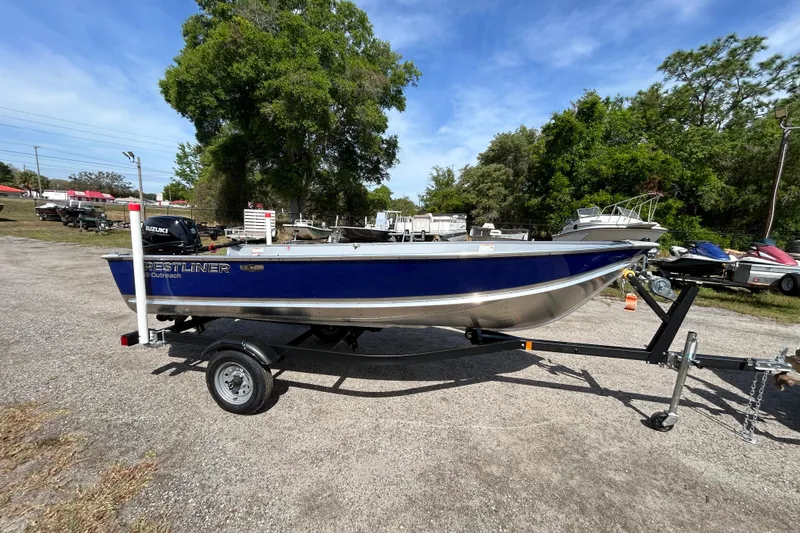 The Image of 2026 Crestliner 1469 Outreach boat on trailer, parked outdoors under clear sky. - 0