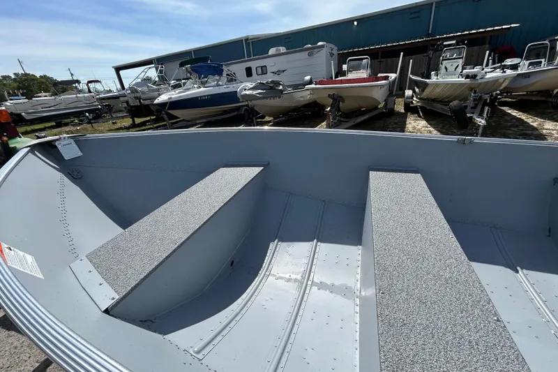 Slide: The Image of 2026 Crestliner 1469 Outreach boat interior with seating, displayed in a boatyard. - 13