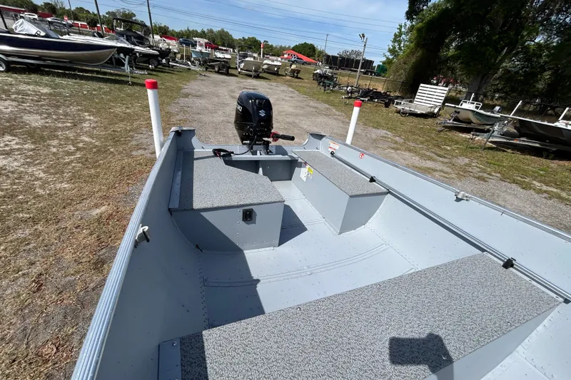 Slide: The Image of 2026 Crestliner 1469 Outreach boat with motor, parked outdoors among other boats. - 6