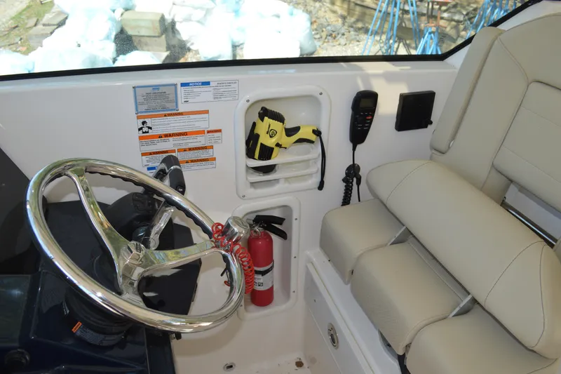 Slide: The Image of 2018 Pursuit DC 295 Dual Console helm with steering wheel, fire extinguisher, and radio. - 10
