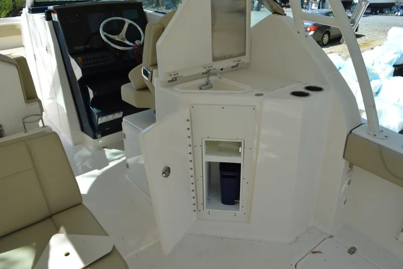 Slide: The Image of 2018 Pursuit DC 295 Dual Console interior with helm, seating, and open storage compartment. - 14