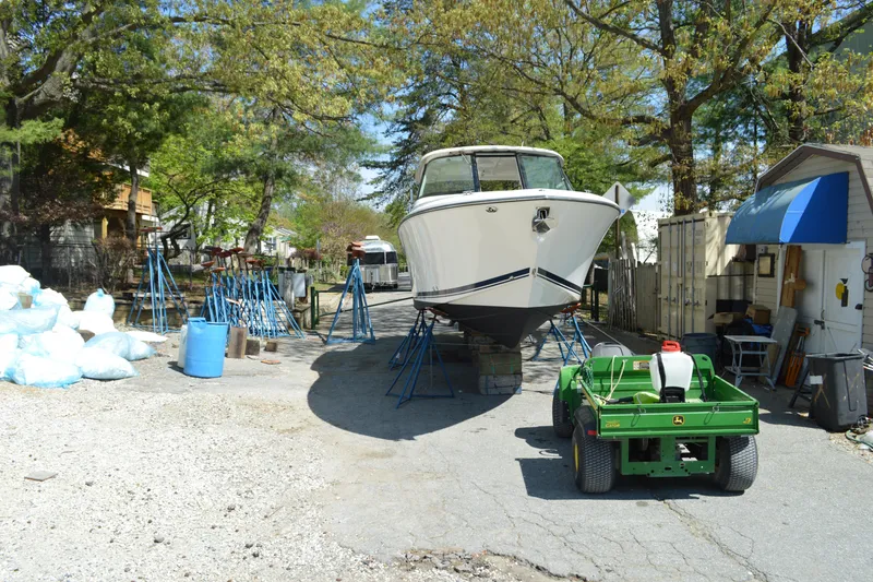 Slide: The Image of 2018 Pursuit DC 295 Dual Console boat on stands in a yard with trees. - 3