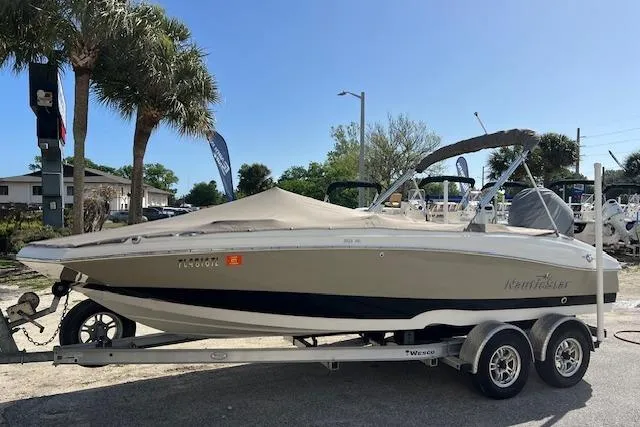The Image of 2018 NauticStar 203SC Sport Deck boat on trailer, parked outdoors. - 0