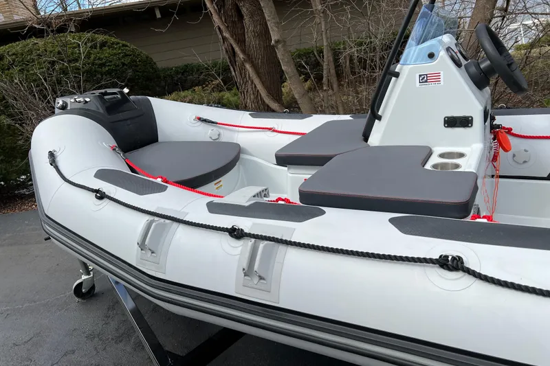 Slide: The Image of 2023 Zodiac Open 4.2 inflatable boat with seating and steering console, parked outdoors. - 14