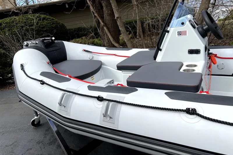 Slide: The Image of 2023 Zodiac Open 4.2 inflatable boat with seating and steering console, parked outdoors. - 2