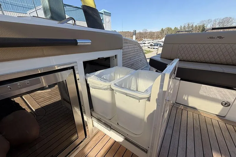 Slide: The Image of 2023 Sea Ray SLX 400 yacht interior with pull-out trash bins and seating area. - 22