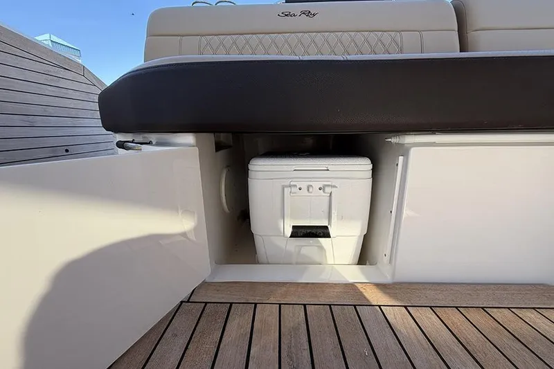 Slide: The Image of 2023 Sea Ray SLX 400 boat storage compartment with cooler on teak deck. - 23