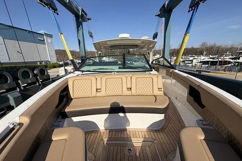 Slide: The Image of 2023 Sea Ray SLX 400 boat interior with tan seating and wood flooring at a marina. - 37
