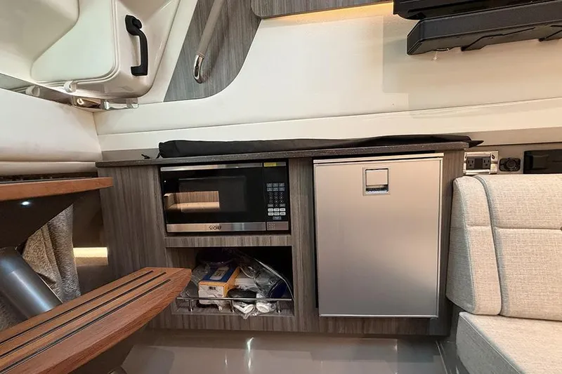 Slide: The Image of 2023 Sea Ray SLX 400 interior with microwave, mini-fridge, and seating area. - 47