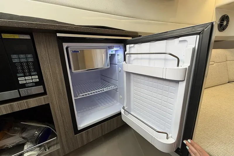 Slide: The Image of Open mini fridge inside 2023 Sea Ray SLX 400 boat cabin, showcasing interior storage space. - 48