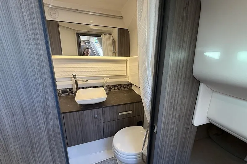 Slide: The Image of 2023 Sea Ray SLX 400 bathroom with modern sink, toilet, and wood cabinetry. - 50