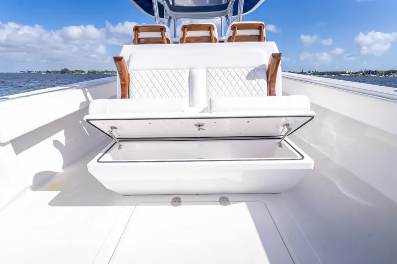 Slide: The Image of 2024 Bahama 41 boat with open storage compartment, white seating, and ocean backdrop. - 16