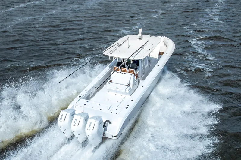 Slide: The Image of 2024 Bahama 41 boat cruising on open water with triple outboard engines. - 27