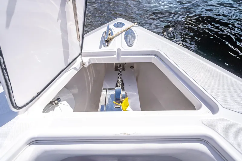 Slide: The Image of Anchor compartment of 2024 Bahama 41 boat, open hatch, stainless steel fittings, calm water background. - 33
