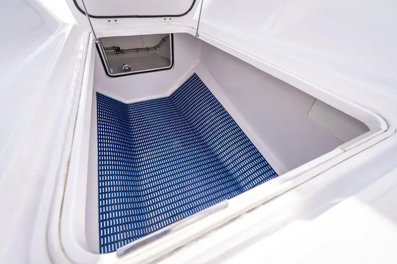 Slide: The Image of Open storage compartment on 2024 Bahama 41 boat with blue grid mat. - 34