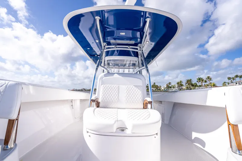 Slide: The Image of 2024 Bahama 41 boat with sleek design, white seating, and blue canopy under a cloudy sky. - 37