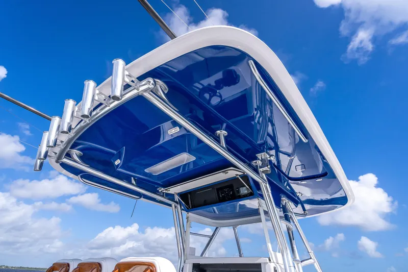 Slide: The Image of 2024 Bahama 41 boat with sleek blue canopy and rod holders against a clear sky. - 49