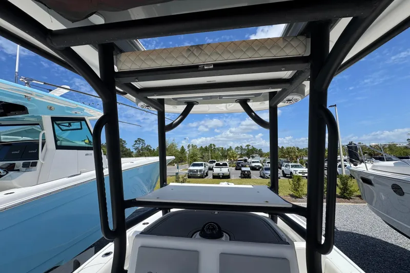 Slide: The Image of 2022 Caymas 26 HB boat interior view with T-top and parked vehicles in background. - 13