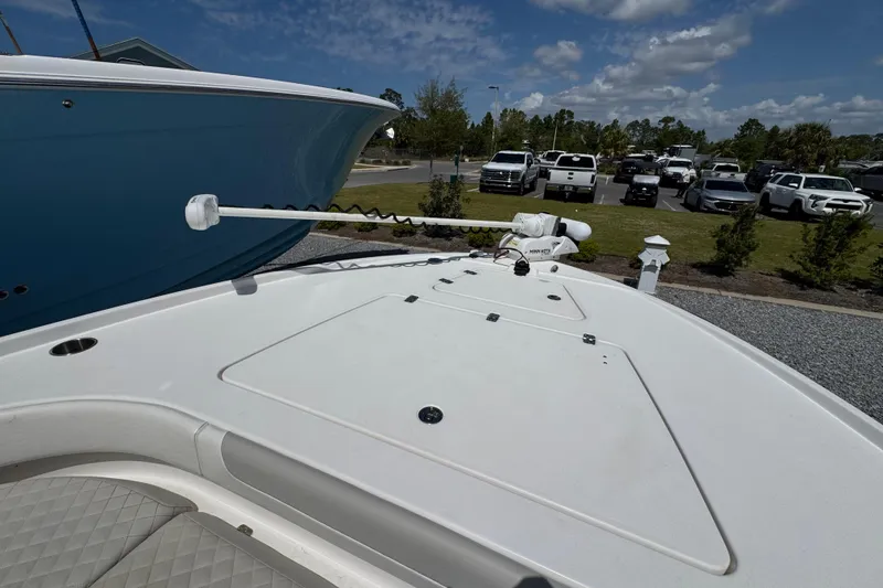 Slide: The Image of 2022 Caymas 26 HB boat deck with trolling motor, parked outdoors under blue sky. - 17