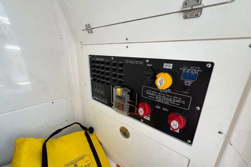 Slide: The Image of Electrical panel of 2022 Caymas 26 HB boat with switches and yellow life jacket nearby. - 18