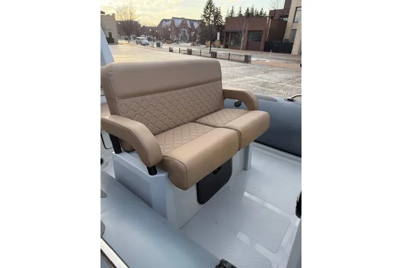 Slide: The Image of 2026 Brig Eagle 6 boat with beige quilted seating, parked outdoors. - 2