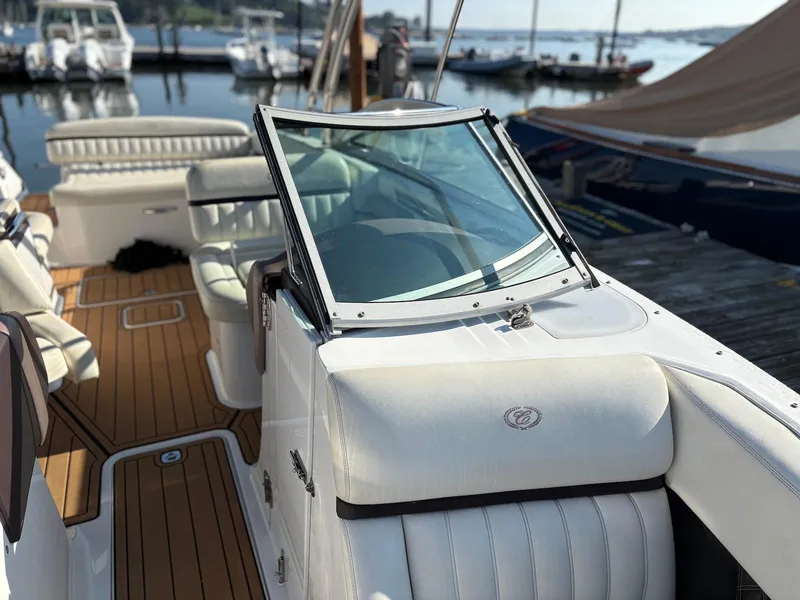 Slide: The Image of 2012 Cobalt A28 boat interior with white seating and wooden deck at a marina. - 22