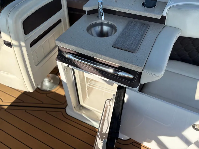 Slide: The Image of 2012 Cobalt A28 boat interior with sink, cutting board, and storage on teak flooring. - 25