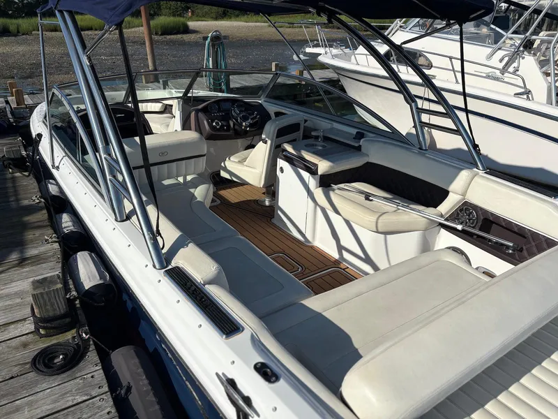 Slide: The Image of 2012 Cobalt A28 boat interior with white seating and wooden flooring at a dock. - 5