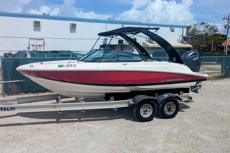 The Image of 2025 Regal 21 OBX boat on trailer, red and white design, parked outdoors. - 0
