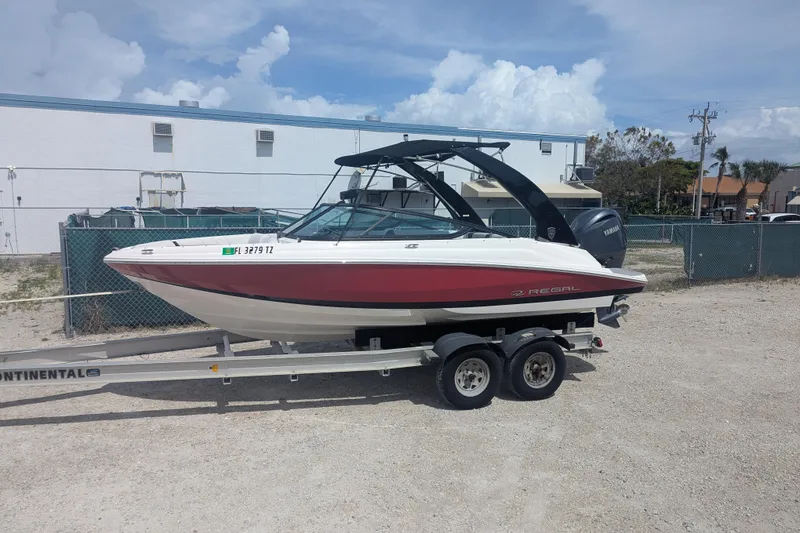 The Image of 2025 Regal 21 OBX boat on trailer, parked outdoors under cloudy sky. - 1