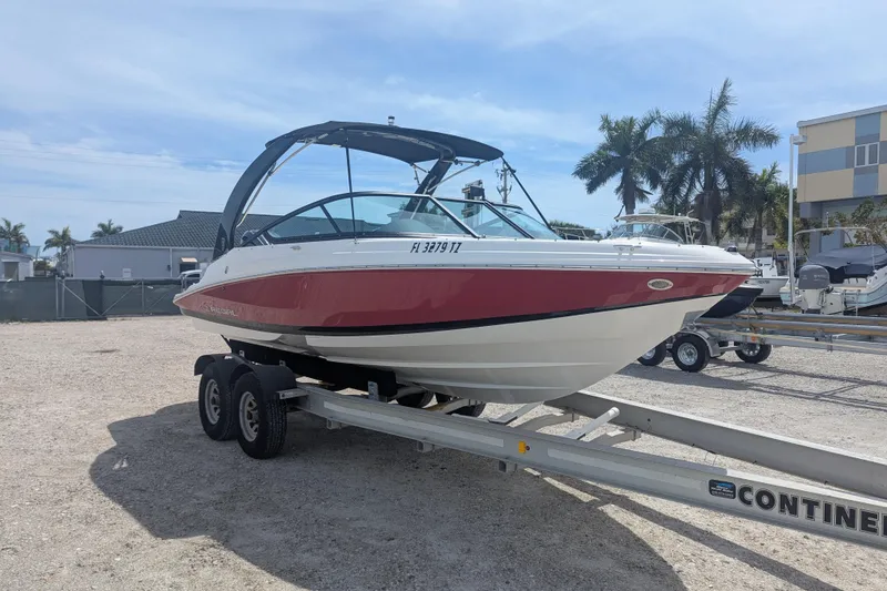 Slide: The Image of 2025 Regal 21 OBX boat on trailer, red and white design, parked outdoors. - 4