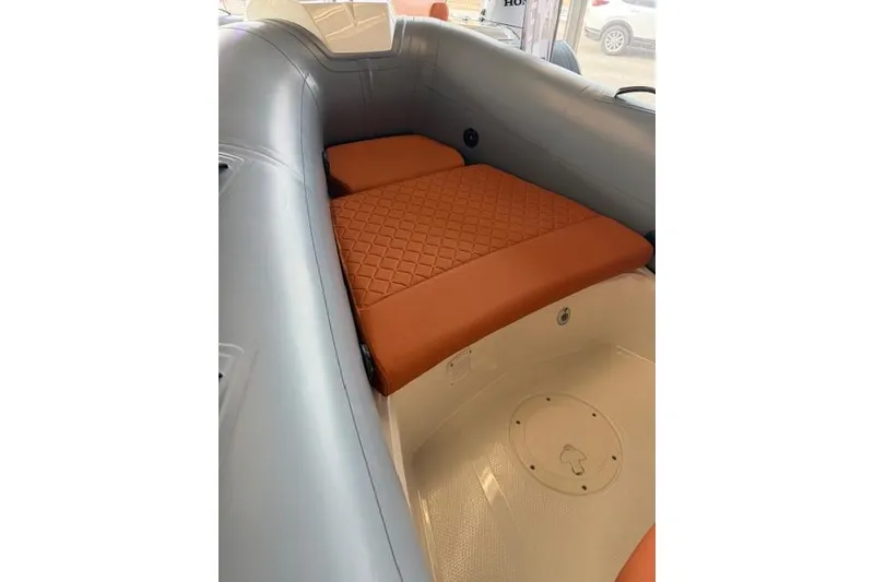 Slide: The Image of 2026 Brig Eagle 5 boat interior with orange quilted seating and gray inflatable sides. - 2