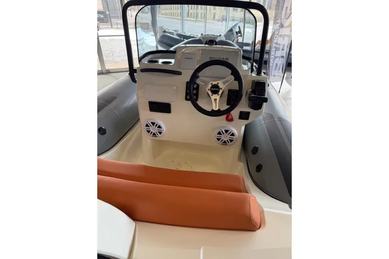 Slide: The Image of Interior view of 2026 Brig Eagle 5 boat with steering wheel and orange seating. - 4