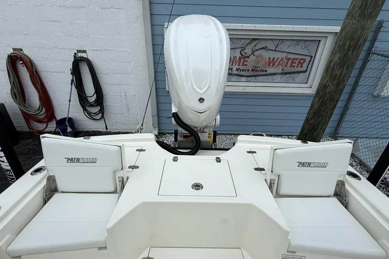 Slide: The Image of 2026 Pathfinder 2500 Hybrid boat with outboard motor, docked near marine shop. - 13