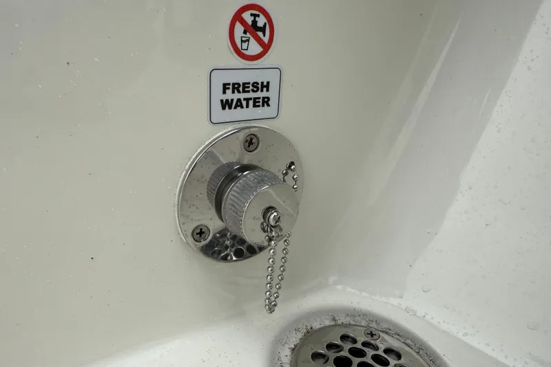 Slide: The Image of Fresh water outlet on 2026 Pathfinder 2500 Hybrid boat, featuring a secure metal cap and chain. - 5