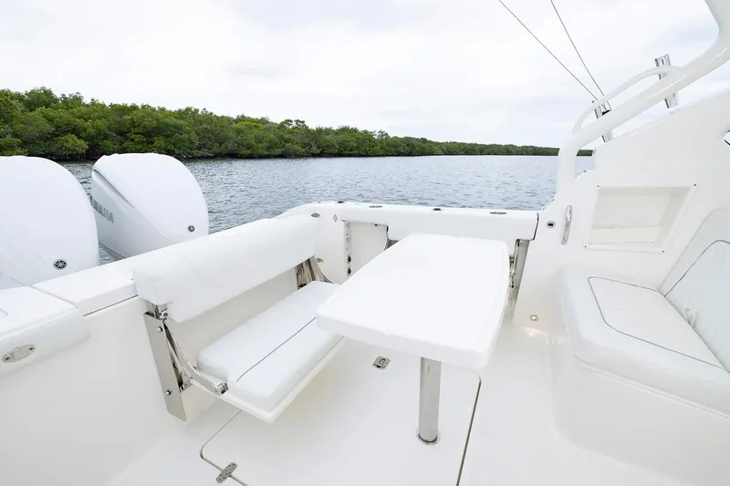 Slide: The Image of Manufacturer Provided Image: 2026 Pursuit DC 286 Dual Console boat interior with seating and table, near water and greenery. - 12