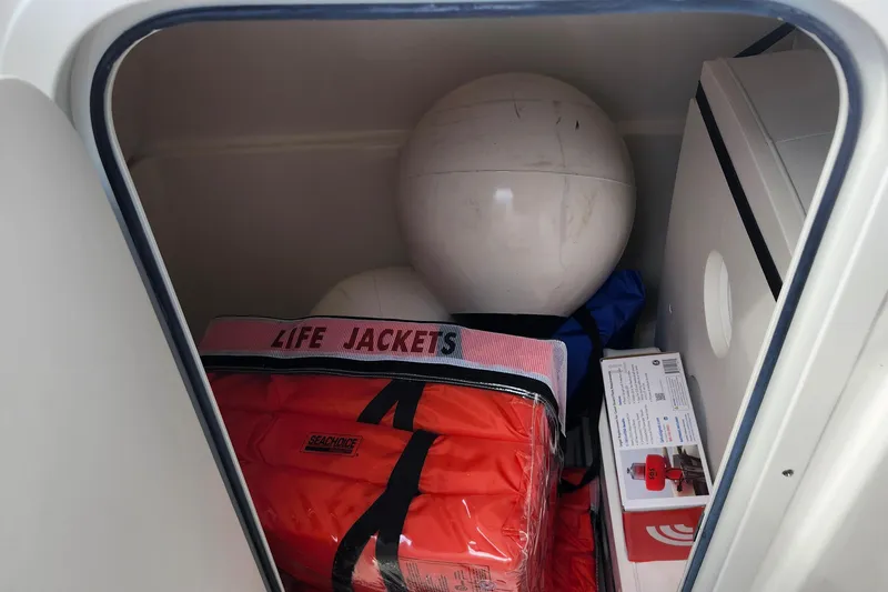 Slide: The Image of Storage compartment of 2026 Pursuit DC 286 Dual Console with life jackets and safety equipment. - 29
