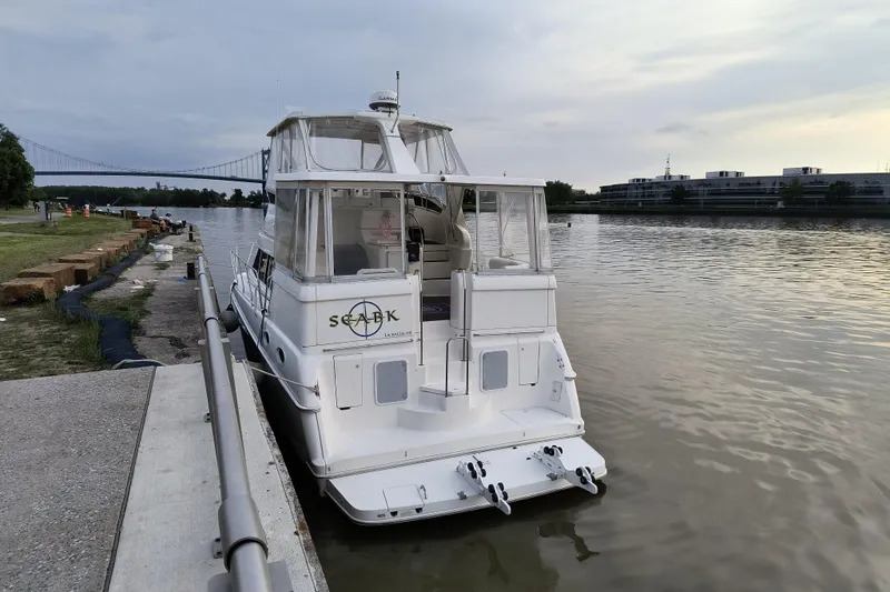 Slide: The Image of 1999 Silverton 422 Motor Yacht docked by a calm river with a bridge in the background. - 104