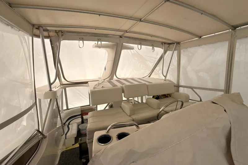 Slide: The Image of 1999 Silverton 422 Motor Yacht interior with seating and helm, enclosed by canvas. - 12