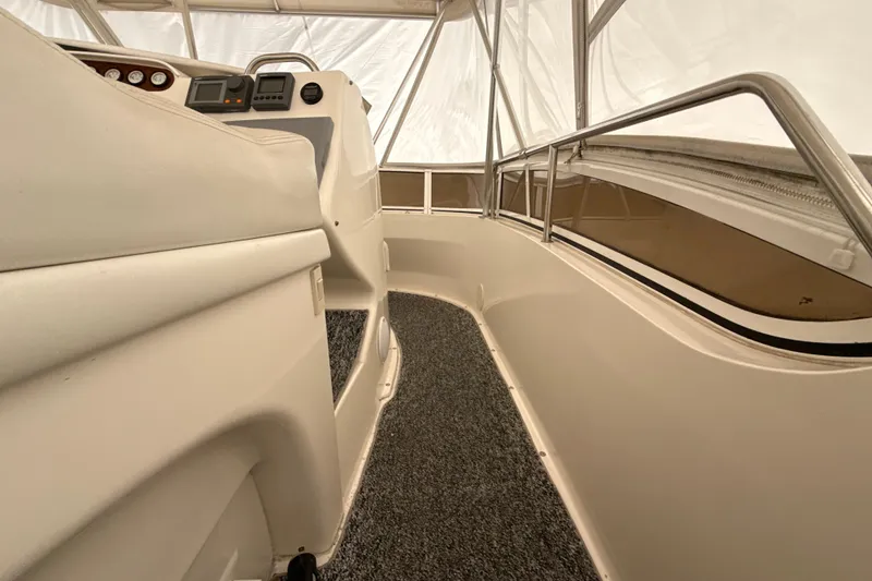 Slide: The Image of 1999 Silverton 422 Motor Yacht interior with helm, controls, and carpeted walkway. - 24