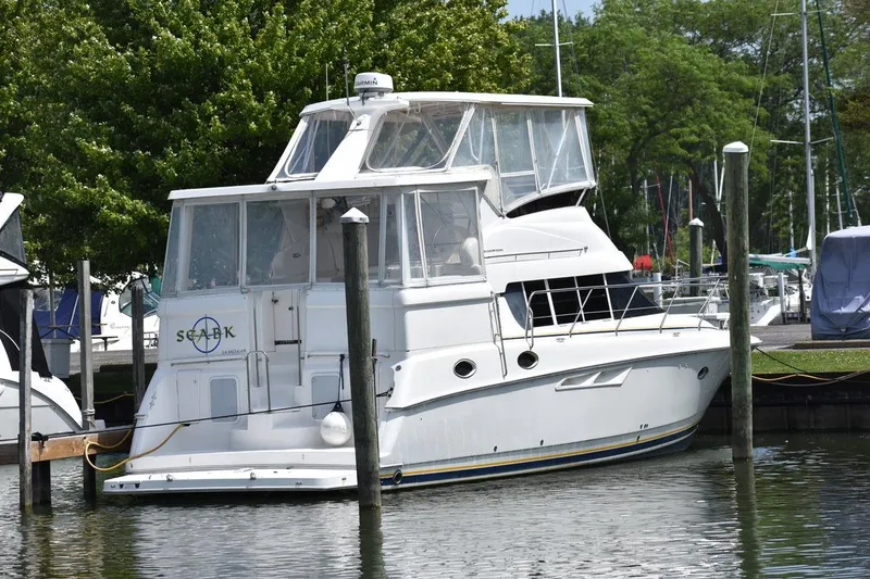 Slide: The Image of 1999 Silverton 422 Motor Yacht docked at marina, surrounded by trees and other boats. - 103