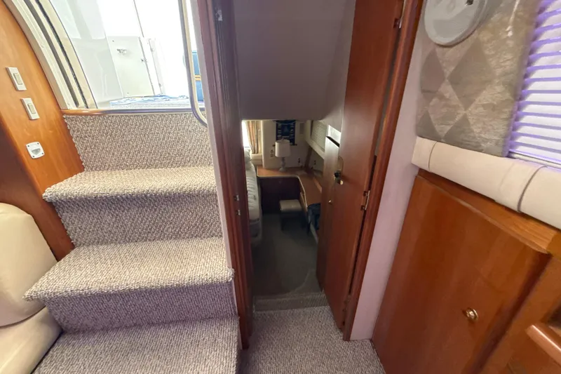 Slide: The Image of Interior view of 1999 Silverton 422 Motor Yacht, featuring carpeted stairs and wooden cabinetry. - 52