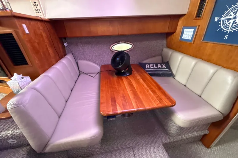 Slide: The Image of Cozy dining area in 1999 Silverton 422 Motor Yacht with plush seating and wooden table. - 56