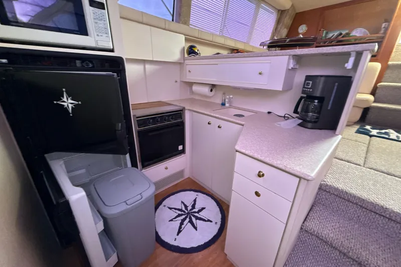 Slide: The Image of 1999 Silverton 422 Motor Yacht kitchen with appliances, white cabinetry, and nautical-themed decor. - 65